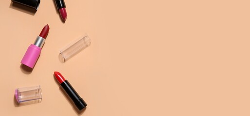 Different lipsticks on beige background with space for text, top view