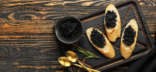 Tasty bruschettas with black caviar on wooden background