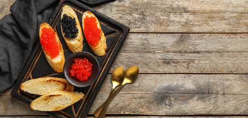 Tasty bruschettas with red and black caviar on wooden background
