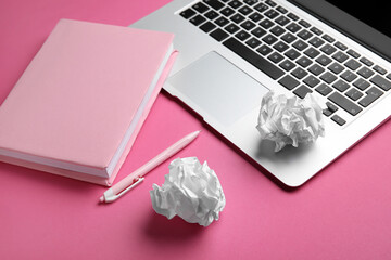 Blank book, pen, crumpled paper balls and laptop on pink background, closeup. World Poetry Day celebration
