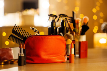 Cosmetic bag with makeup accessories and lipsticks on dressing table in room