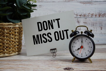 Don't Miss Out text with alarm clock on wooden background