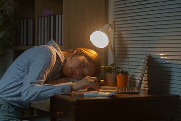 Young Asian office worker falling asleep at workplace with laptop and calculator, struggling with burnout and exhaustion