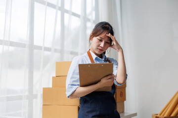 Young business woman with headache managing online orders and feeling stressed because of too much...