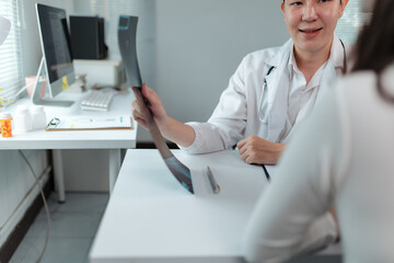 Female doctor discussing radiography results with her patient, providing detailed explanations of...
