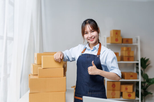 Young entrepreneur giving a thumbs up while managing online store deliveries, radiating confidence and satisfaction in her thriving business