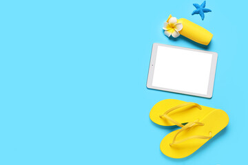 Composition with modern tablet computer, flip-flops and bottle of sunscreen on color background