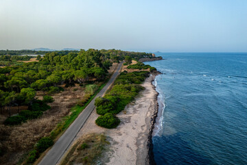 Obraz premium Drone aeriall view of coastal road winding through green vegetat