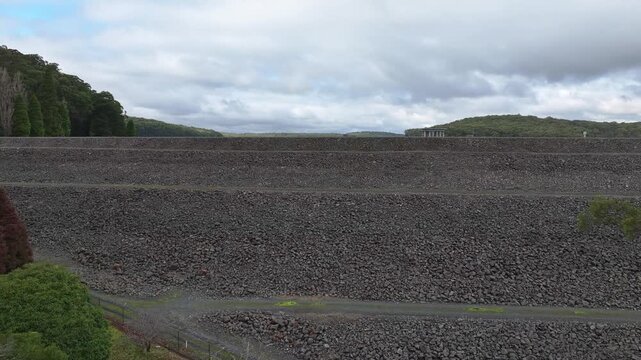Silvan Reservoir intake tower sits in still water under grey skies and tree lined banks
