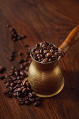 Coffee beans in the turkish dzezva coffee pot on wooden background.