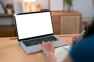 A woman is working on a laptop with a blank white screen at home