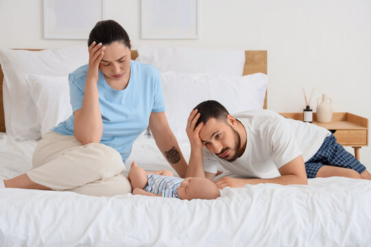 Tired parents with their little baby in bedroom