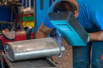 Master replacing of  muffler of exhaust system in car workshop. Car pipe 
exhaust welding