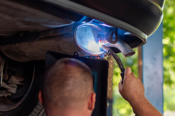 Master replacing of  muffler of exhaust system in car workshop. Car pipe 
exhaust welding