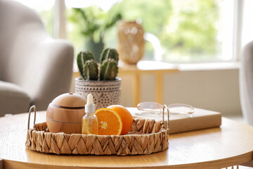 Tray with air humidifier, essential oil and oranges on table in living room, closeup