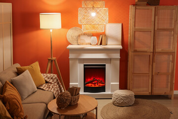 Fireplace with sofa, closet and glowing lamps near orange wall in living room