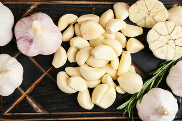 Fresh garlics and rosemary on wooden board, closeup