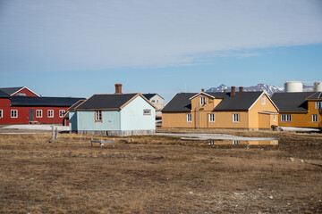 Obraz premium Colorful buildings at the base of snow covered mountans in the research base at Ny Alesund, Svalbard, Norway