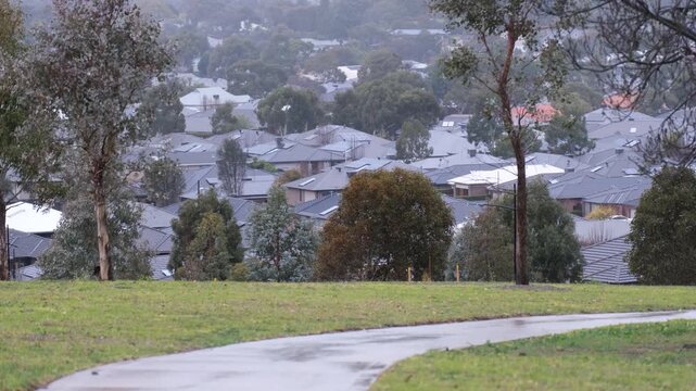 Suburban rooftops in Doreen, Victoria, viewed from an elevated parkland on a cold and rainy winter day. Concept of residential housing in a modern outer Melbourne neighborhood.