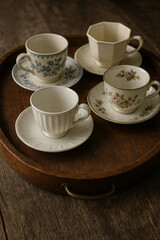 Fototapeta premium Assorted vintage teacups and saucers on wooden tray