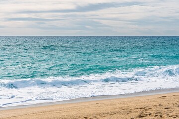 This beautiful seascape showcases the peaceful ocean meeting the shore. With turquoise water, white waves, and golden sand, it evokes relaxation and is perfect for coastal themes.