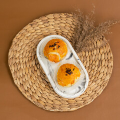 Two golden brown bakpia with glossy egg wash and chocolate sprinkles on top, served on a white...