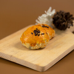 Two pieces of golden-brown bakpia with chocolate sprinkles on top, placed on a wooden serving board...