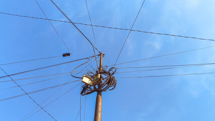 Steel electric utility tower photographed against bright blue daytime sky. Industrial high voltage...