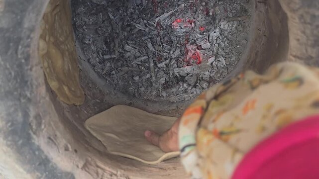 Traditional tandoor oven baking process, rustic clay oven with burning charcoal and flatbread, authentic middle eastern bread making culture