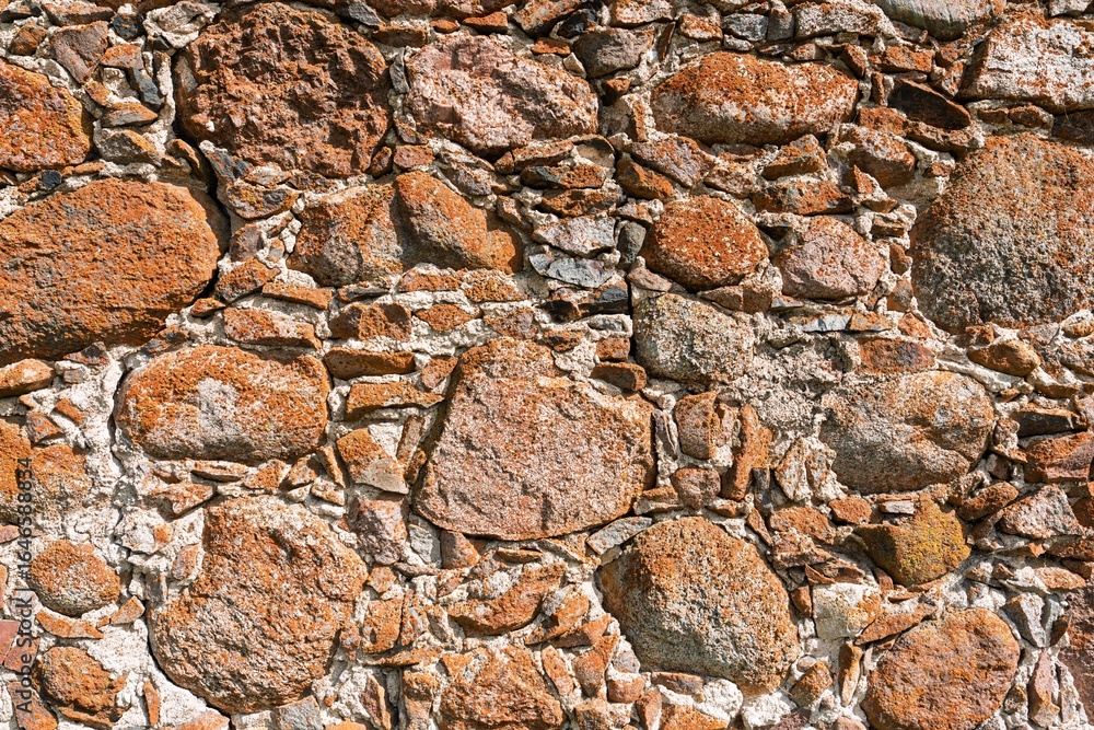 Aufkleber a weathered stone wall with a rugged texture showcases an array of colorful brown and gray rocks. th