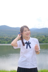 A girl wearing a white shirt and black skirt is smiling and holding a red. A Student girl concept