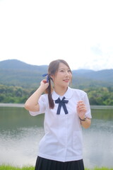 A girl wearing a white shirt and black skirt is standing by a lake. A Student girl concept