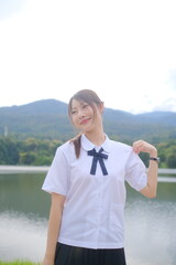 A girl wearing a white shirt and black skirt poses for a picture by the water. A Student girl...