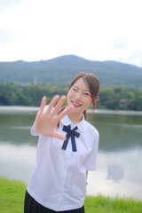 A girl in a white shirt and black skirt is posing for a picture by the water. A Student girl concept