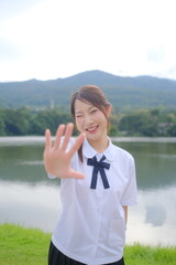 A girl in a white shirt and black skirt is standing by a lake. A Student girl concept