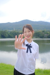 A girl in a white shirt and black skirt is posing for a picture by the water. A Student girl concept
