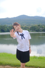 A girl in a school uniform is posing for a picture by the water. A Student girl concept