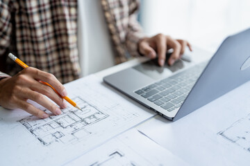 Fototapeta premium Architectural Drawing of Building Project with Colleagues Designing Blueprint Using Compasses