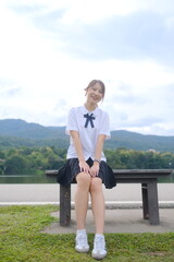 A girl is sitting on a bench in a park. A Student girl concept