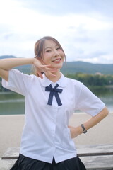A girl wearing a white shirt and black skirt is smiling and posing for a picture. A Student girl...