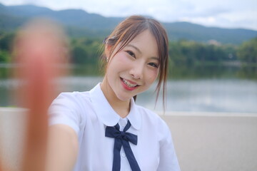 A young woman with a smile on her face is taking a selfie with her finger. A Student girl concept
