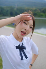A woman wearing a white shirt and a blue bow tie is standing on a road. A Student girl concept