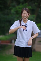A young woman in a school uniform is smiling and pointing her finger. A Student girl concept