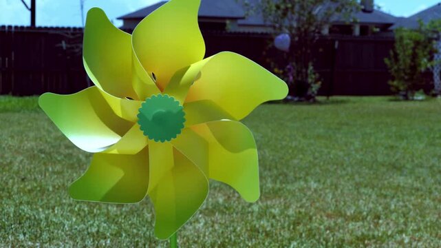 Yellow pinwheel gently turning blowing in the wind of a residential backyard with grass and trees behind it 