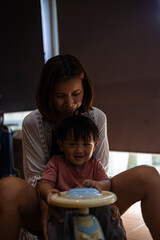 Mother And Toddler Riding A Toy Car In The House