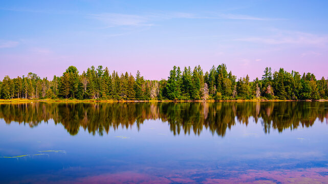 Early autumn sunrise landscape over Flagstaff Lake in Maine with water reflections of the pine forests, a quiet moment in the heart of New England.