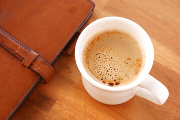 Brown schedule planner, diary, notebook with cup of Coffee on table
