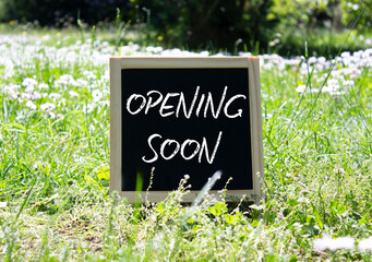 Opening soon symbol. Concept word Opening soon on chalk blackboard. Beautiful meadow background....