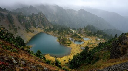 High-elevation alpine lakes nestled in a rugged mountain valley, shrouded in a misty, overcast sky