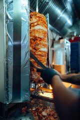 Fast Food Chef Cutting Roasted Meat with Doner Knife. Professional cook working in a restaurant...